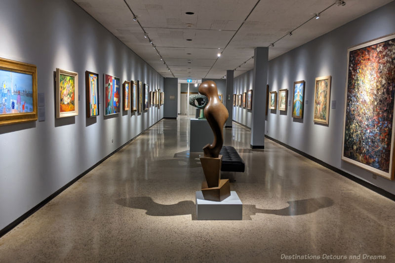 Rectangular art gallery space with sculptures down the centre and paintings on the walls