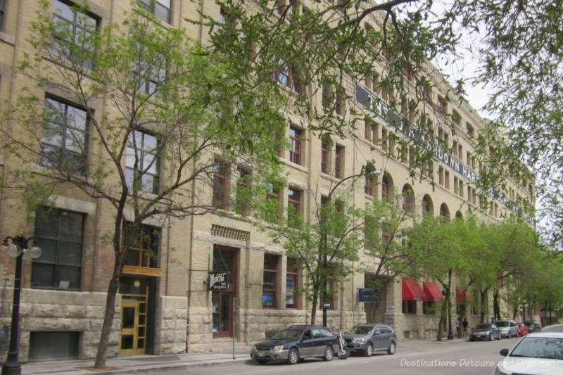 Winnipeg Ashdown Warehouse Brick several story former warehouse now converted to commercial and residential space along paved street with trees planted in sidewalk