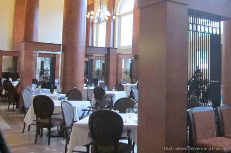 Exchange District Jane's Restaurant tables covered in white tablecloths in a tall-ceilinged room with marble pillars and ornamentation