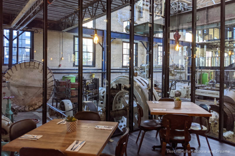 Exchange District James Avenue Pumphouse Restaurant dining tables in front of a full window wall behind which lays old pump house equipment