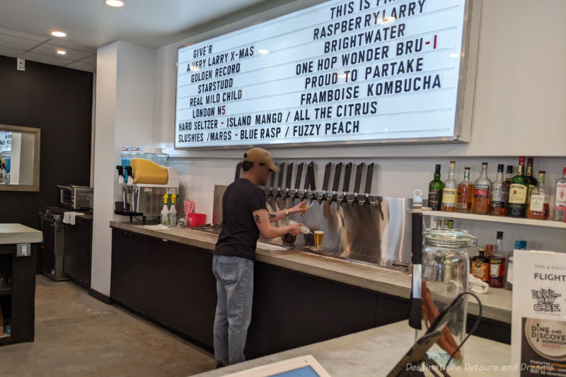 Devil May Care Taps Man pouring beer from one of 16 taps in a brewery taproom