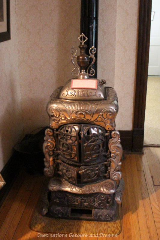 Metal heating stove with intricate design in its metal and a stovepipe to heat more of house