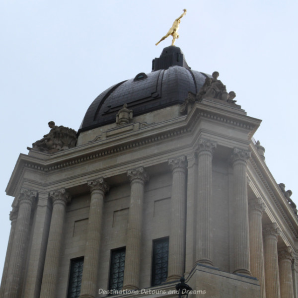 Stone columns at the top of a building supporting a dome with the figure of the Golden Boy atop it