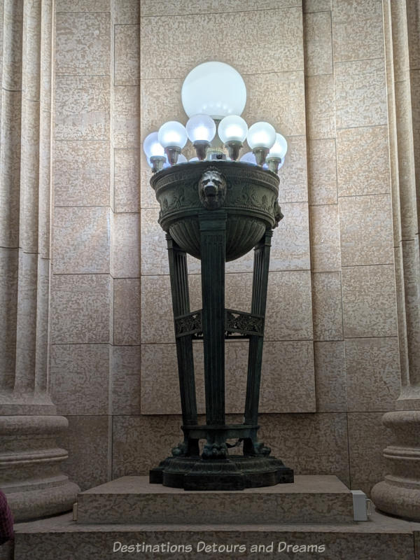 Metal based lamp with designs etched in it and containing 13 globed bulbs on top