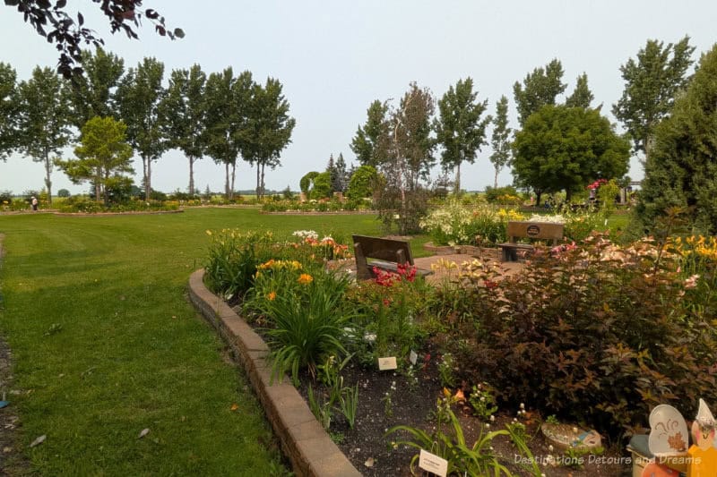 Beausejour Daylily Gardens Green Space Tree-lined grassed park with brick-lined garden beds of blooming flowers