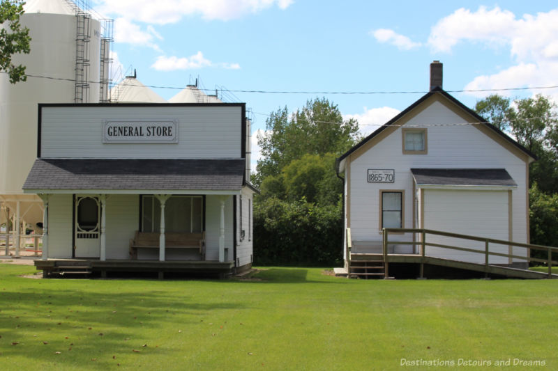 Two white one-story wooden buildings part of a heritage village museum